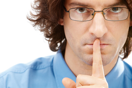 Portrait of serious businessman with glasses holding his finger over the mouth